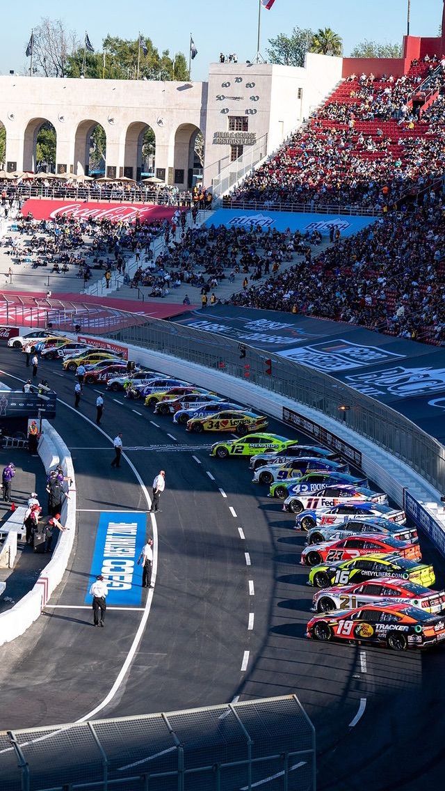 the cars are lined up on the race track in front of an audience at a sporting event