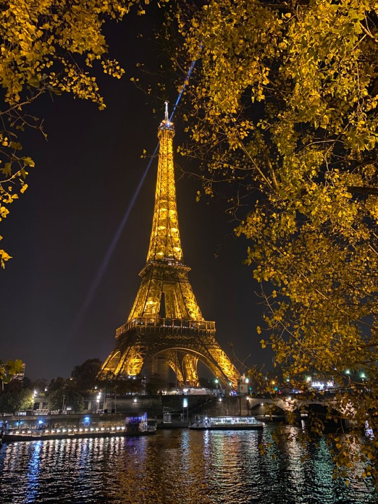 the eiffel tower lit up at night from across the river in paris, france