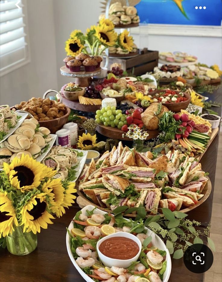 a table filled with lots of food on top of a hard wood floor covered in sunflowers