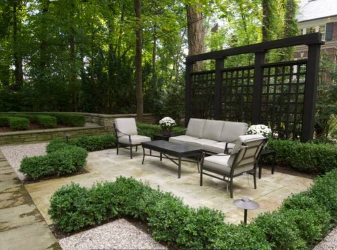 an outdoor seating area with couches and tables surrounded by greenery in the background