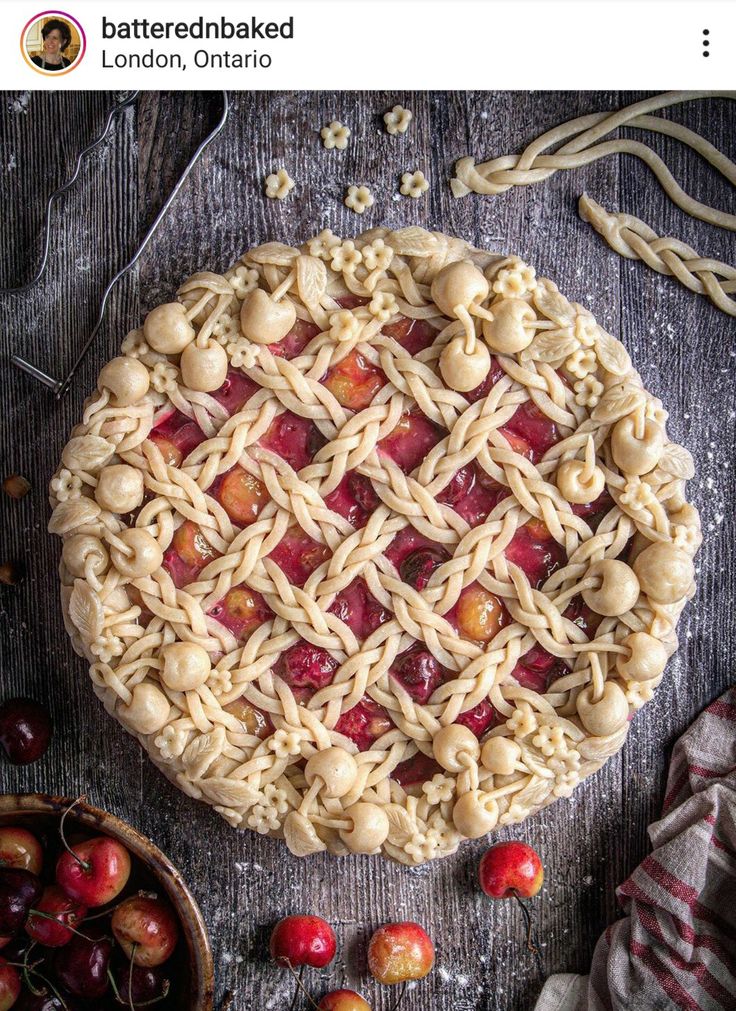 an apple pie with latticed crust and cherries around it