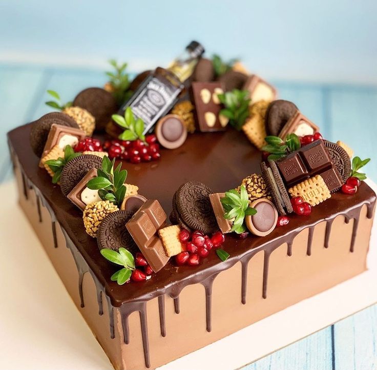 a heart shaped cake with chocolates and berries on it's side, sitting on a table