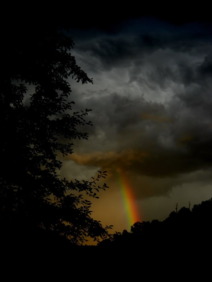 a rainbow in the sky with dark clouds