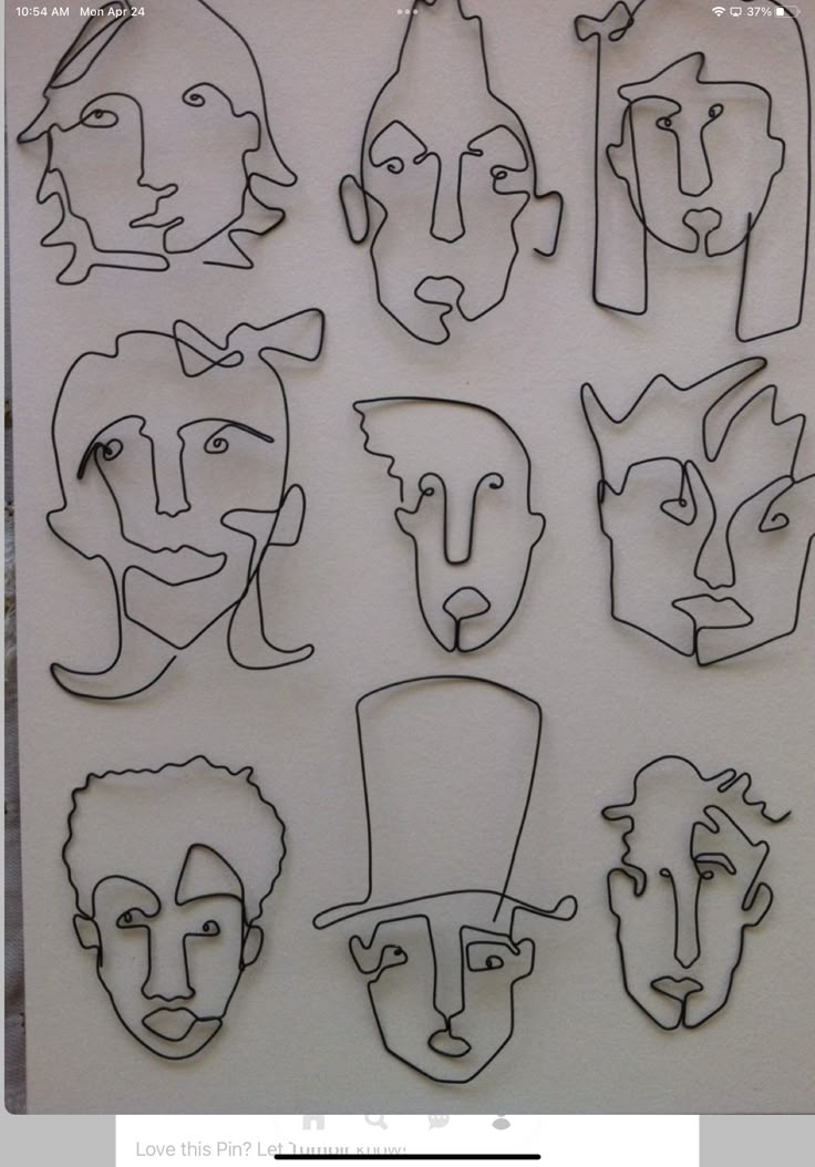 a group of paper cut out of faces on a white sheet with black lines in the middle