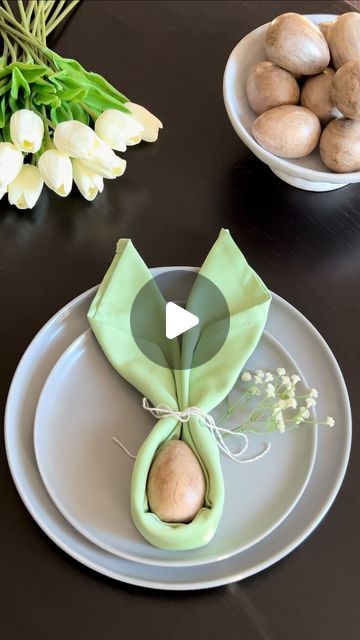 the table is set with two plates and three bowls filled with flowers, one has an ornament on it