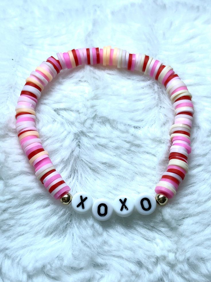 a pink and white beaded bracelet with the word xoxo written on it