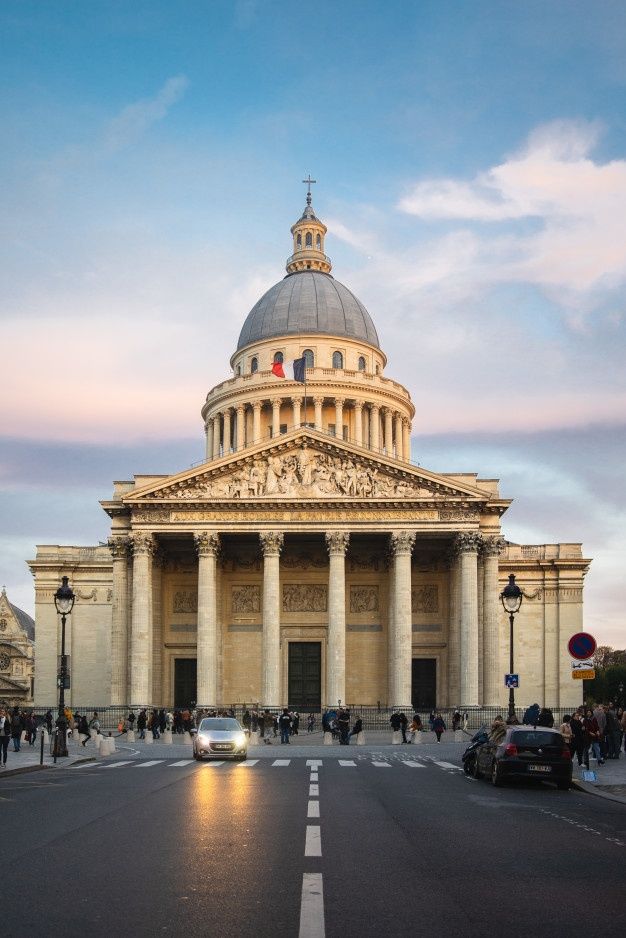 a car is driving down the street in front of a building with columns and a dome