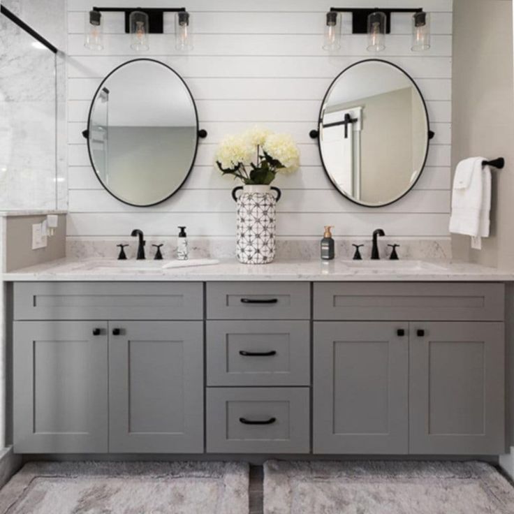 a bathroom with two sinks, mirrors and flowers in vases on the counter top