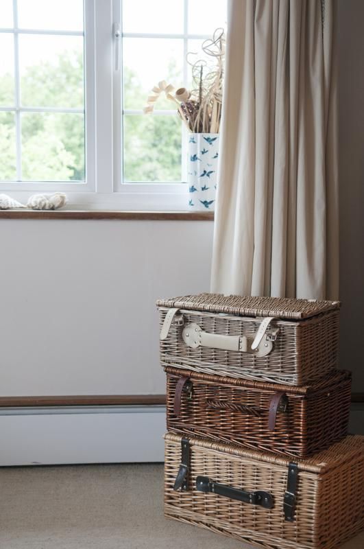 two wicker suitcases sitting next to each other in front of a window with curtains