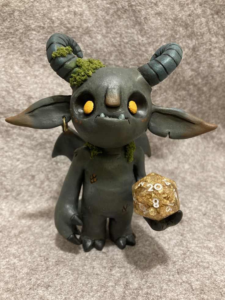 a toy with horns holding a rock and wearing a gold ball in it's hand