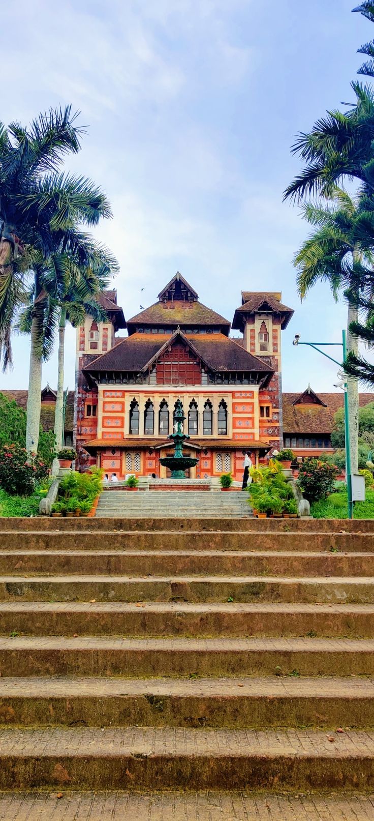 an old building with palm trees and steps leading up to the front door, on a sunny day