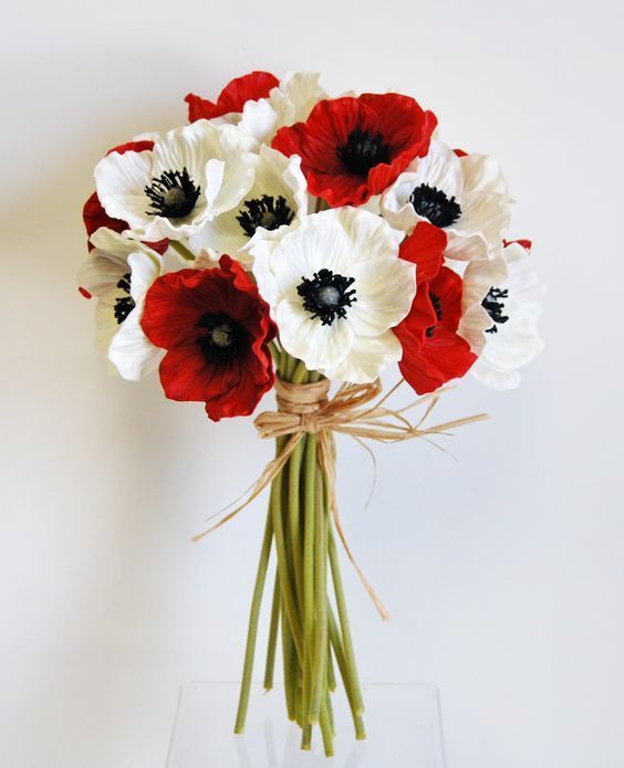 a bouquet of white and red flowers in a clear glass vase on a table top