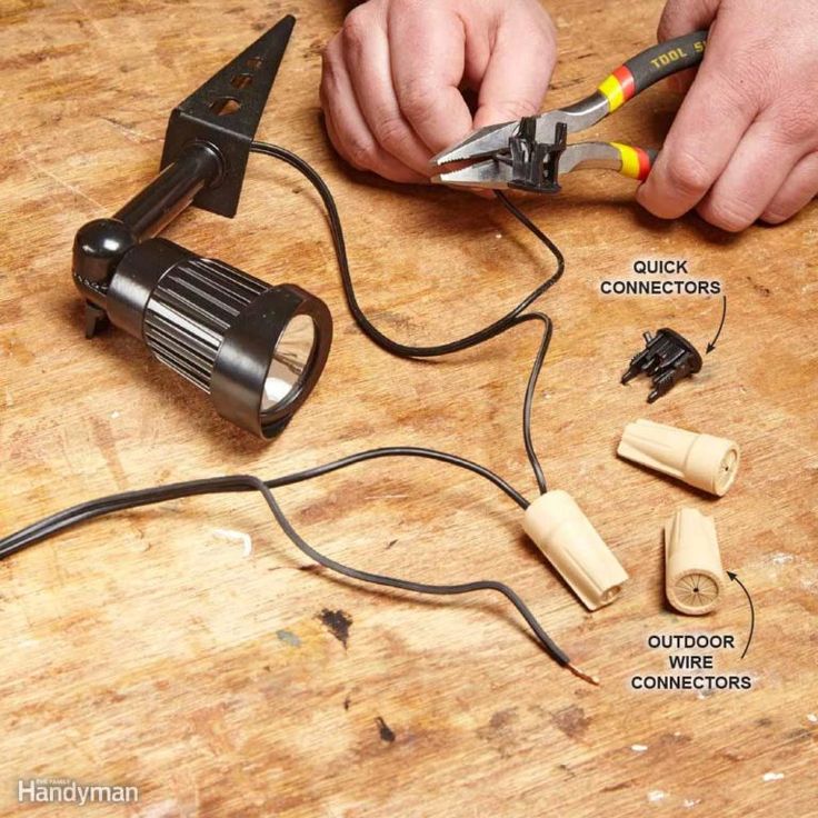 a man is working with some electrical equipment on a wooden table, including wire cutters and wires