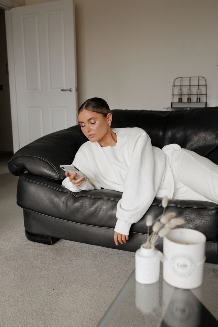 a woman laying on a couch looking at her cell phone