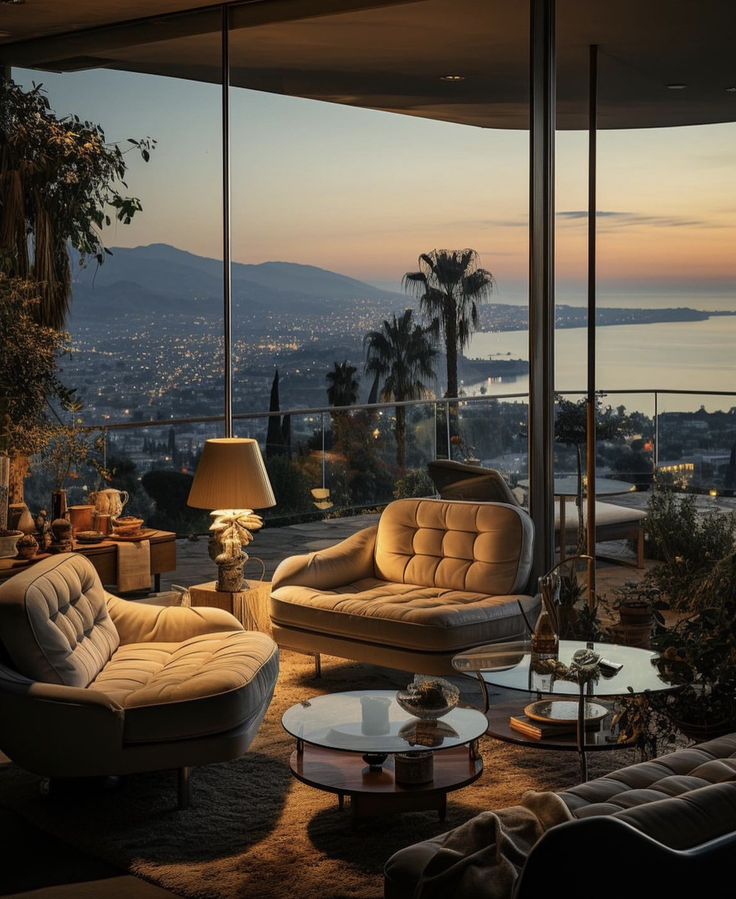 a living room filled with furniture and a view of the ocean at sunset or dawn