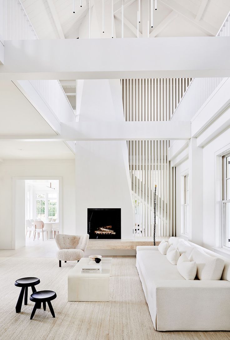 a living room filled with white furniture and a fire place in the middle of it