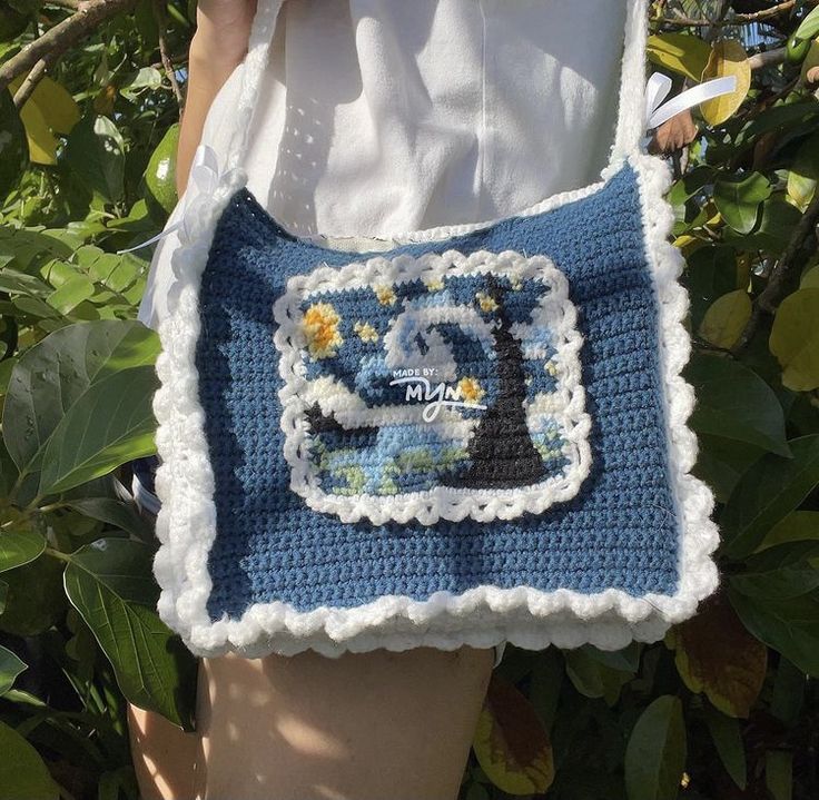 a woman holding a crocheted bag with an image of a boat on it