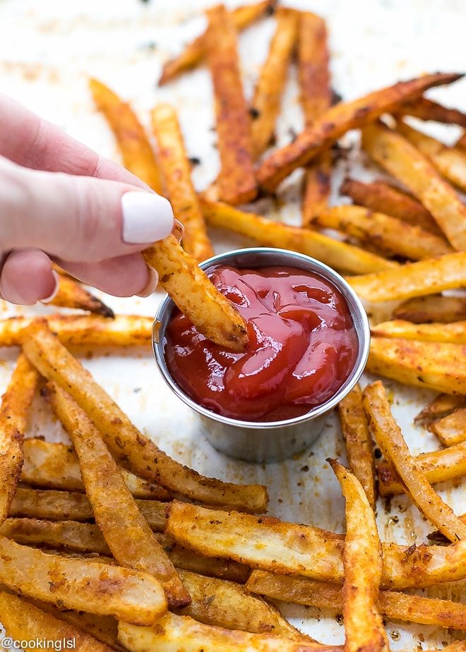 a person dipping ketchup into french fries