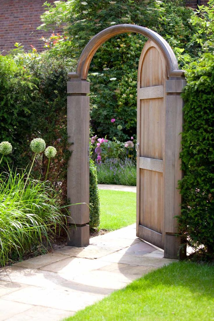 an open wooden door in the middle of a garden