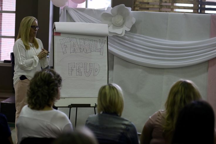 a woman standing in front of a group of people while giving a presentation to them