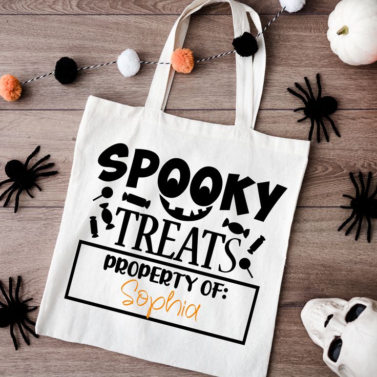 spooky treats tote bag on wooden table with halloween decorations