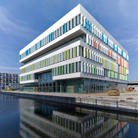 an office building with multicolored windows next to the water in front of it