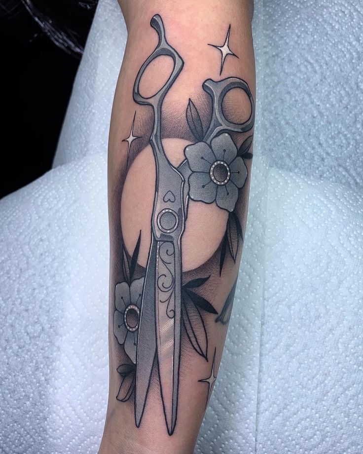 a tattoo with scissors and flowers on it