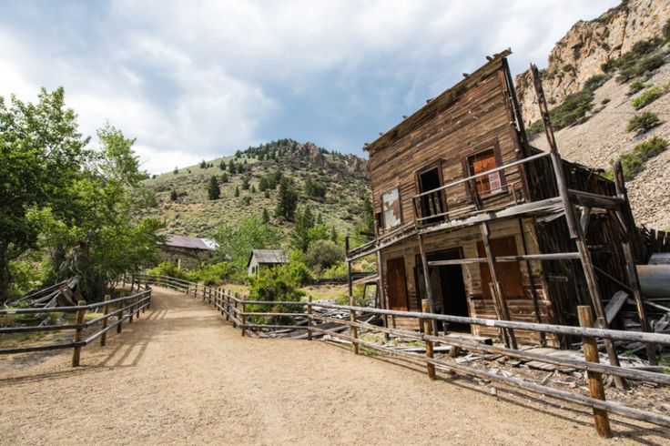 an old wooden building sitting on top of a dirt road