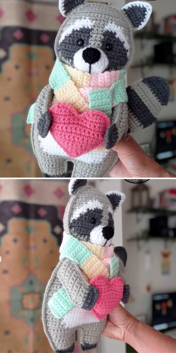 crocheted stuffed raccoon holding a heart in it's arms and wearing a scarf around its neck