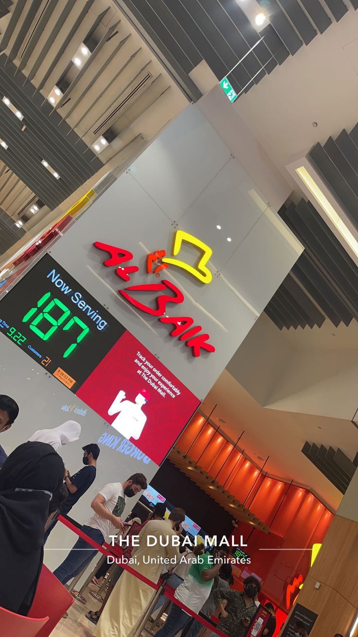 people are standing in line at the entrance to an airport terminal with signs on the wall