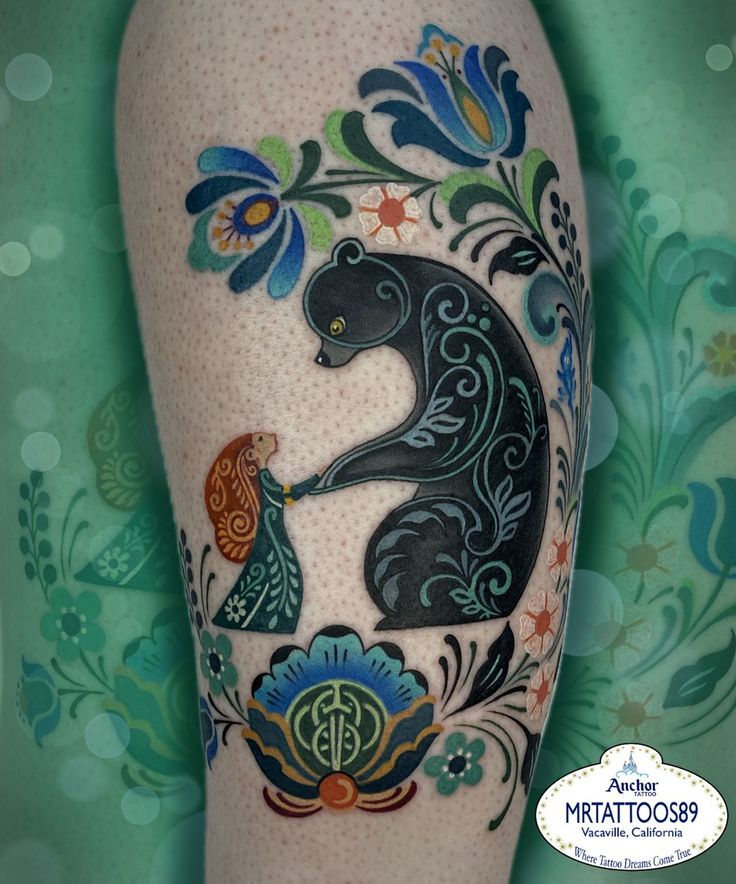 an artistic tattoo on the leg of a woman's legs with flowers and cats