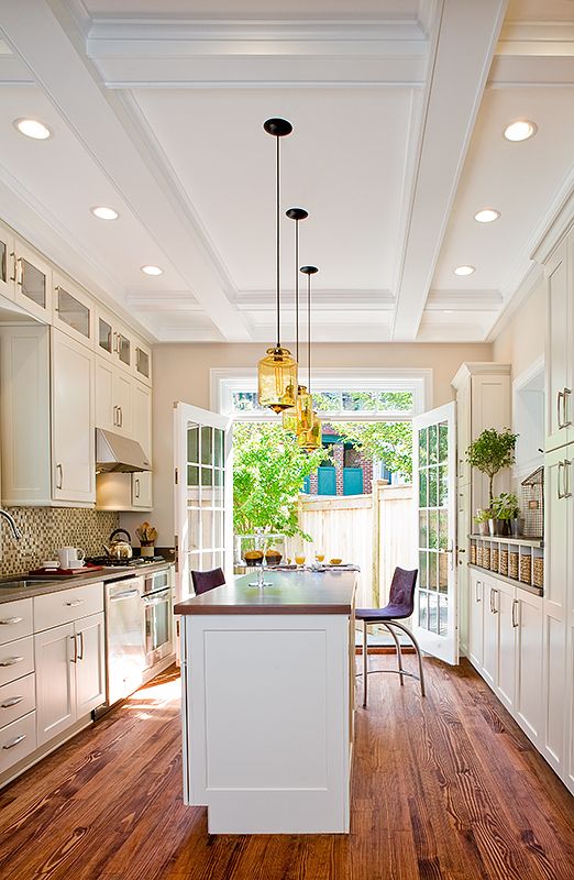 a large kitchen with white cabinets and wood flooring, along with an island in the middle