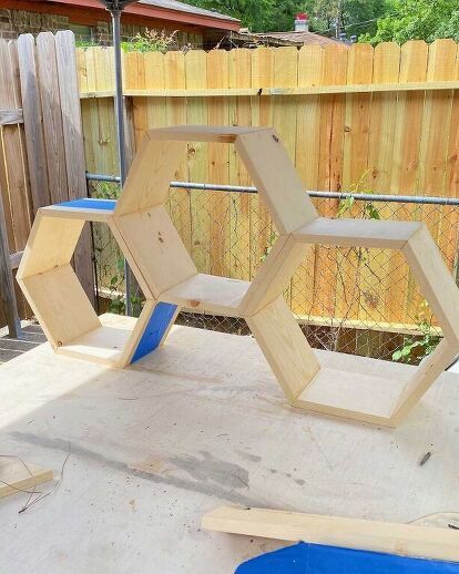 a wooden structure sitting on top of a cement ground next to a blue plastic object