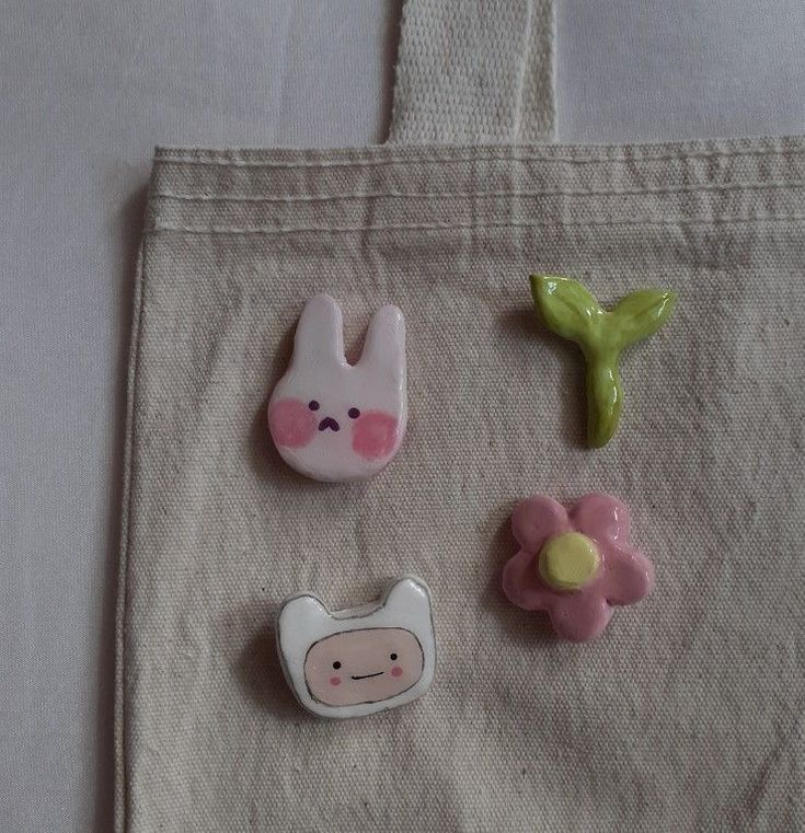 three small plastic animals sitting on top of a white tote bag next to each other