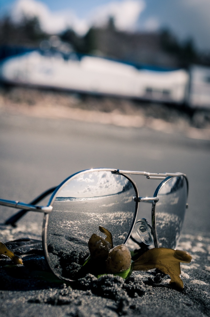 a pair of sunglasses sitting on top of a sandy beach next to a banana peel