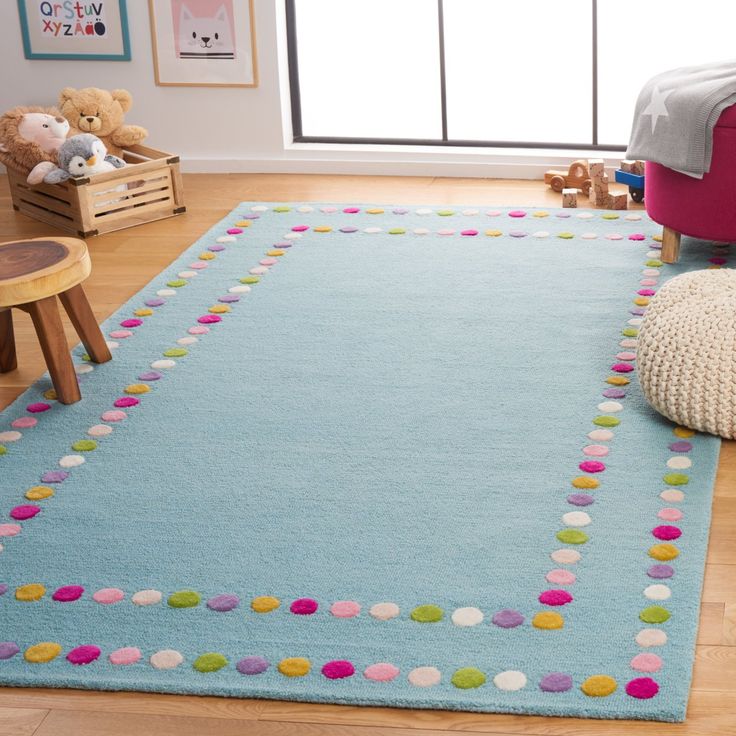 a child's room with a blue rug and teddy bear on the floor in front of it