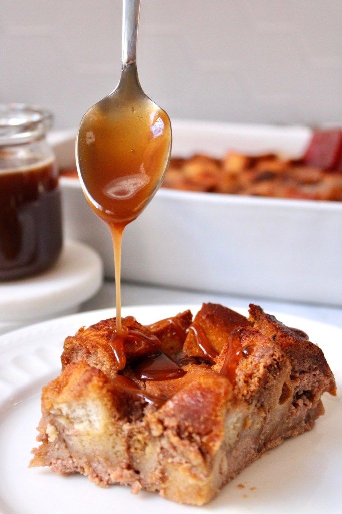 a spoon drizzling caramel sauce onto a piece of bread on a plate