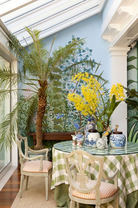 a dining room table with two chairs and a potted palm tree in the corner