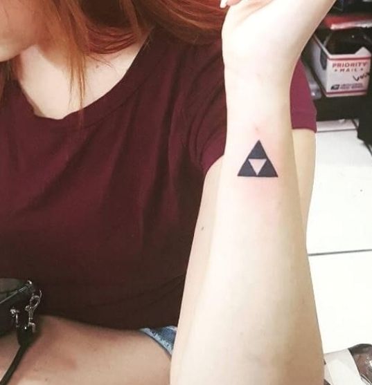 a woman with a small triangle tattoo on her left arm, sitting at a table