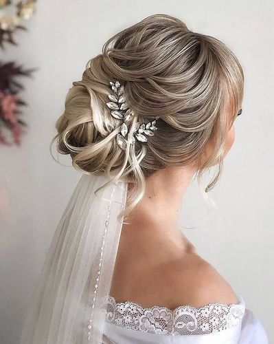 a bride with her hair in a low bun, wearing a veil and bridal hairstyle