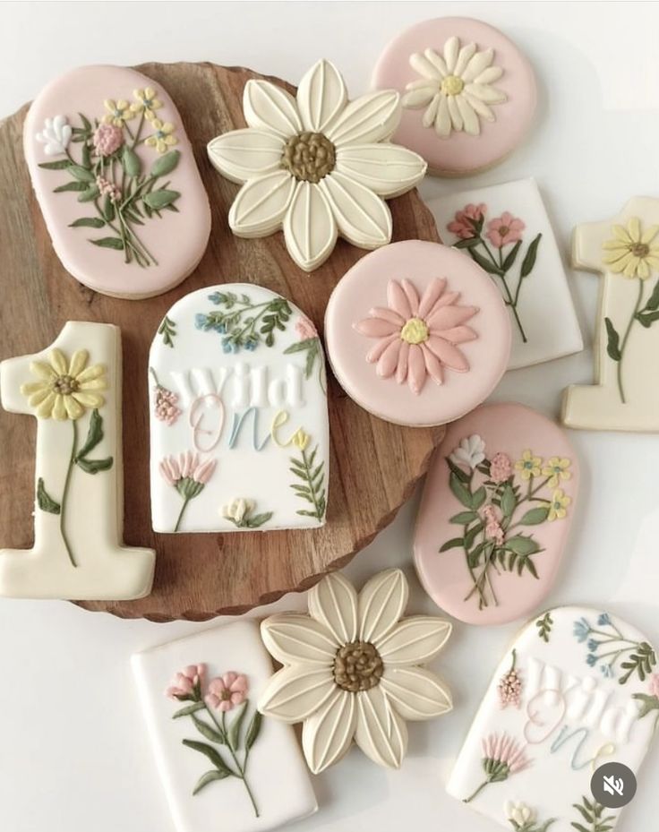 cookies decorated with flowers and the letters i - v are on a wooden platter