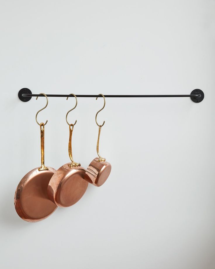 three copper pots hanging from a black hook