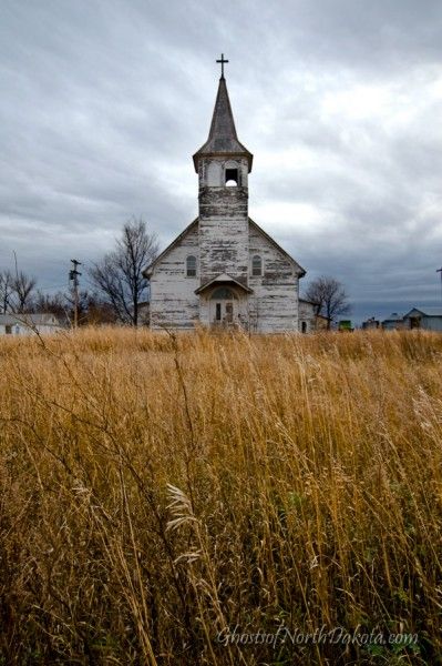 an old church sits in the middle of tall grass