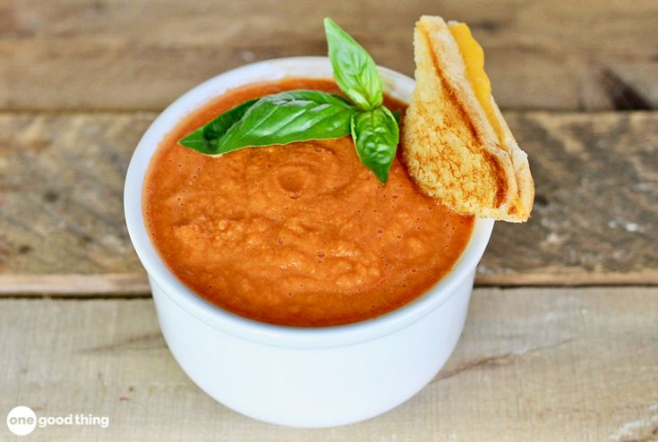 a small white bowl filled with red sauce and chips on top of a wooden table