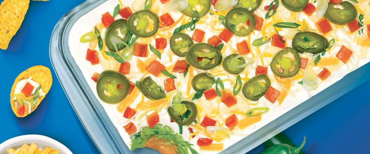 a casserole dish with peppers, cheese and tortilla chips on the side