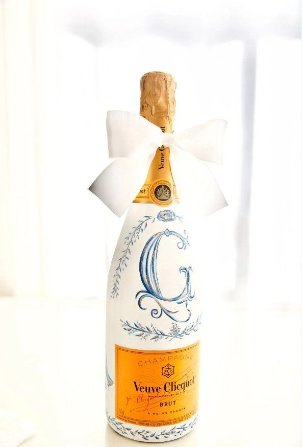 a bottle of wine with a white bow on it's top and the letter g