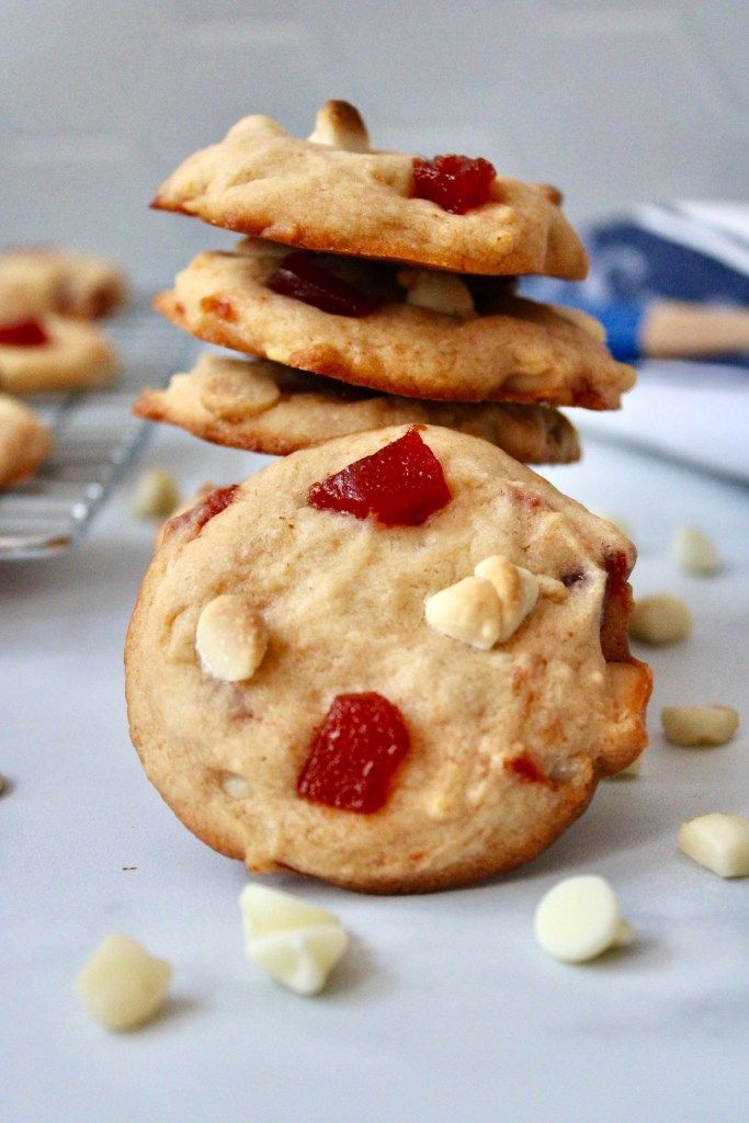 three cookies stacked on top of each other with white chocolate chips scattered around the cookies