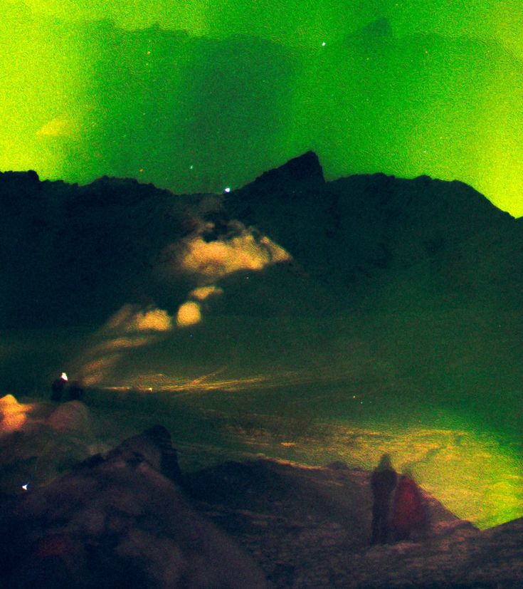 an aurora bore is seen in the sky over mountains