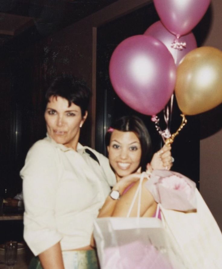 two women standing next to each other holding shopping bags and balloons