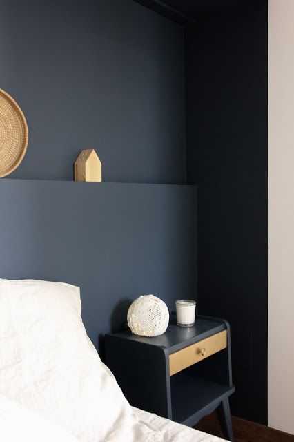 a white bed sitting next to a blue wall with a basket on top of it